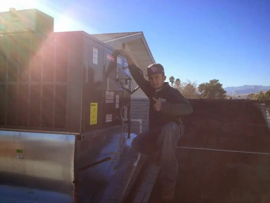 HVAC technician performing Heat Pump Repair on a rooftop unit in Peters