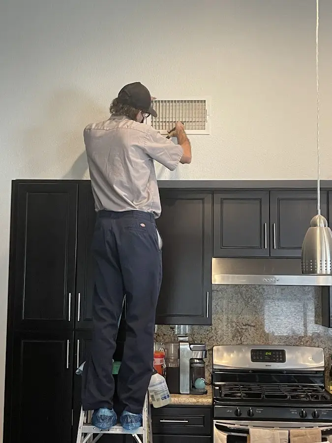 Technician inspecting an air vent during HVAC service in Peters
